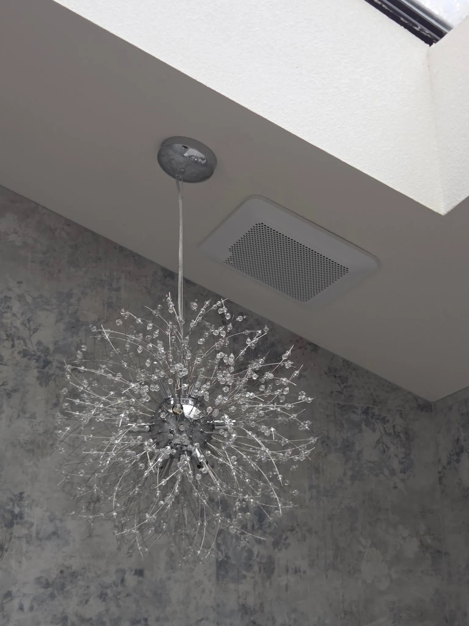 Bathroom exhaust fan installed above a decorative ceiling fixture