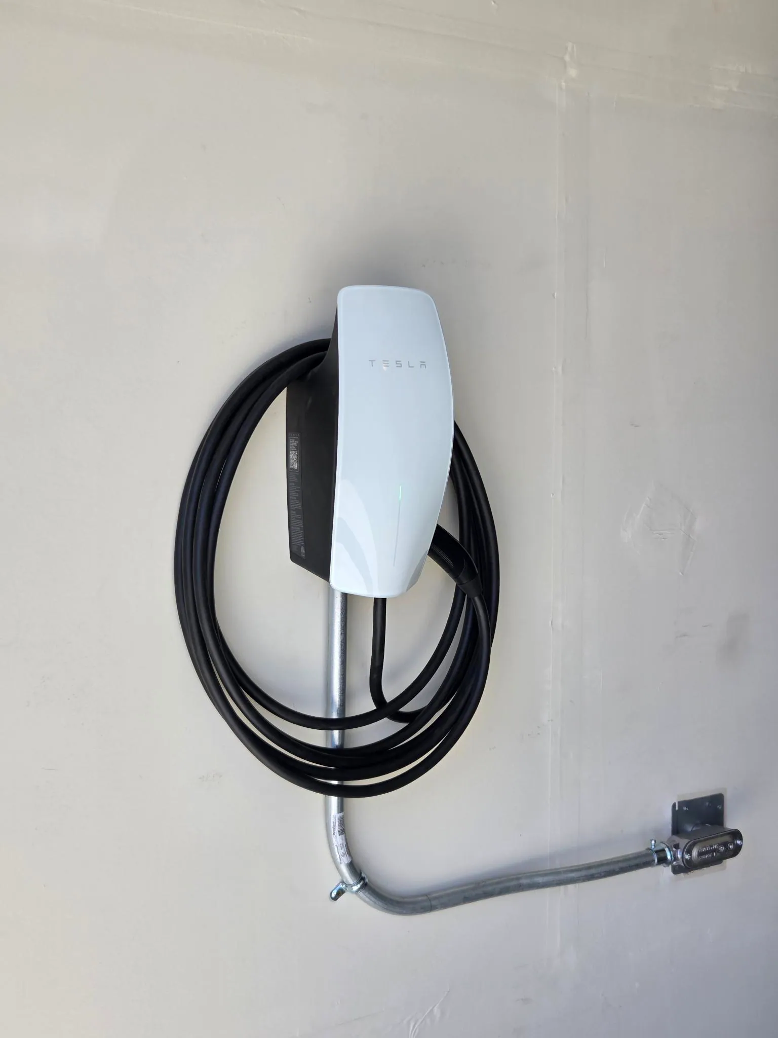 Side view of a Tesla wall connector and metal conduit